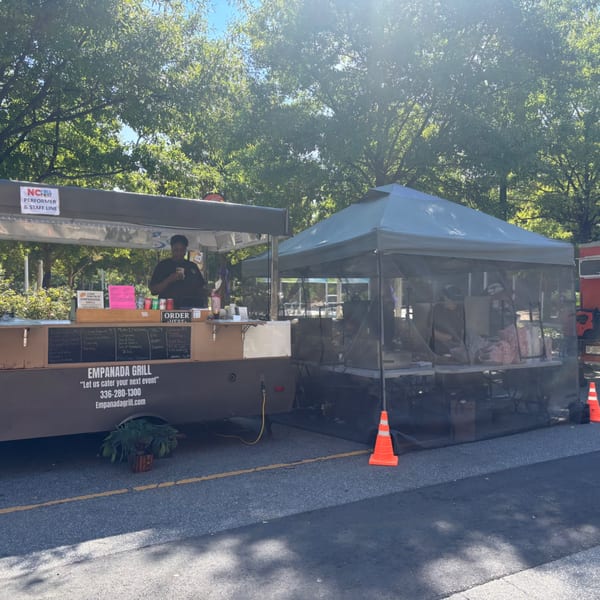 Empanada Grill food truck with a server, menu, and a separate tent for food preparation.