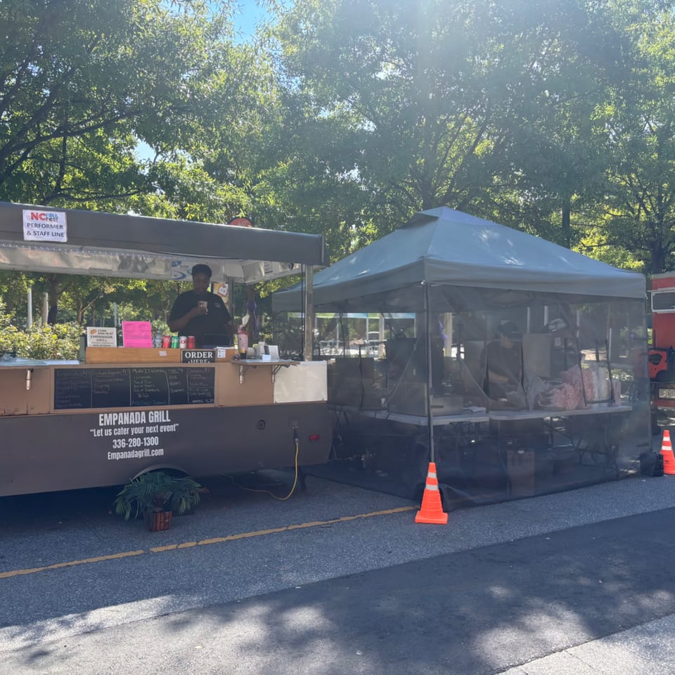 Empanada Grill food truck with a server, menu, and a separate tent for food preparation.